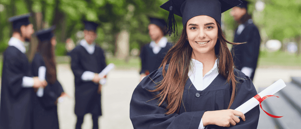 A young woman wearing a cap and gown is holding her high school diploma.