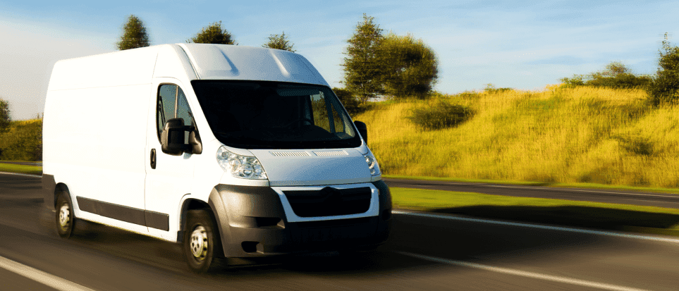 White van driving fast on a highway.