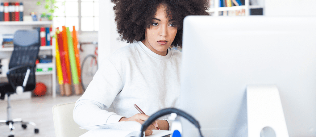 A woman is working at her laptop and learning how to do a background check for employment.