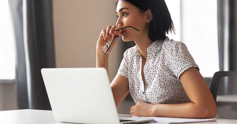 Young woman sitting at desk with computer thinking about adverse action